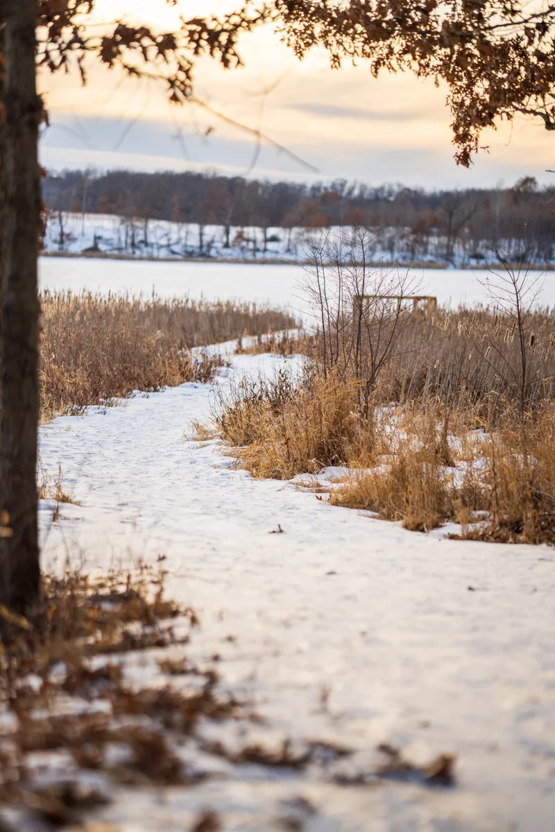 frozen winter trail leading out to a lake side pier