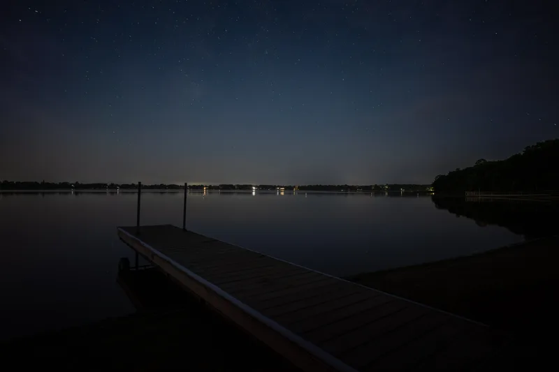 star lit pier on a calm night lake
