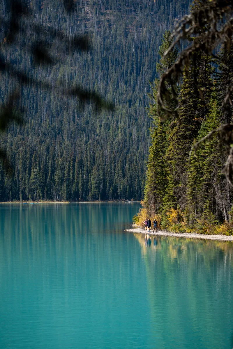 group of people hiking around emerald lake on the shore