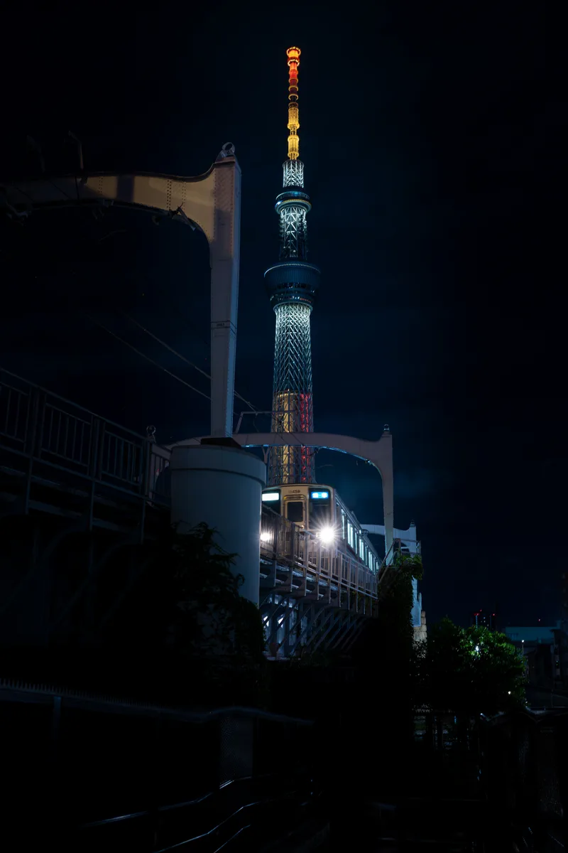 train approching at night in front of the tokyo skytree
