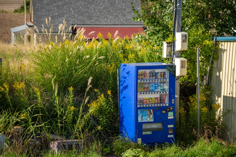 japanese vending machine sitting in a rural field in central hokkaido