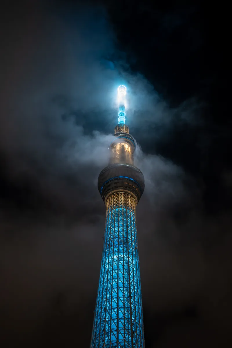 the tokyo skytree glowing on a night with low lying clouds